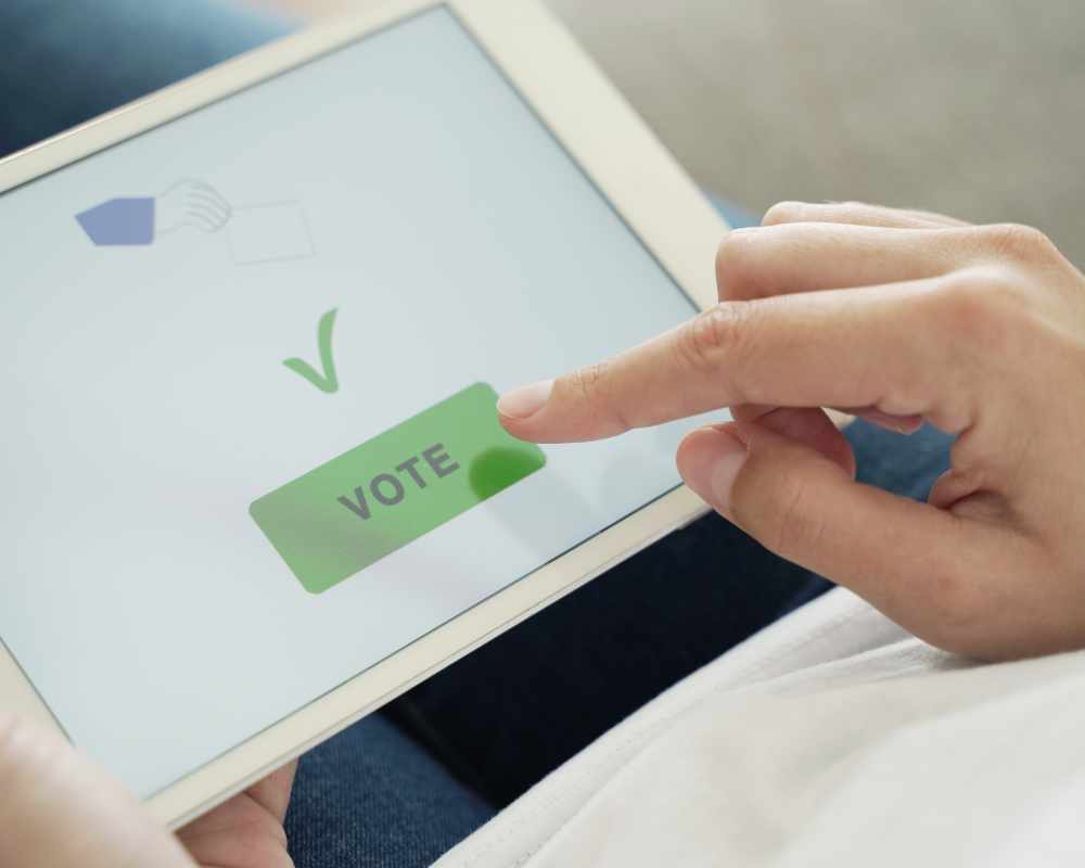 Image of a person tapping a button reading "Vote" on a tablet
